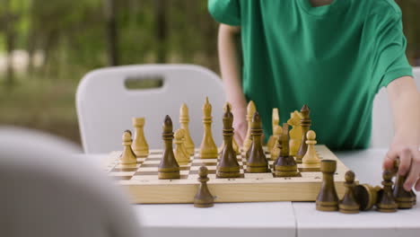 Little-boy-setting-up-a-chess-board-at-the-camping-in-the-forest