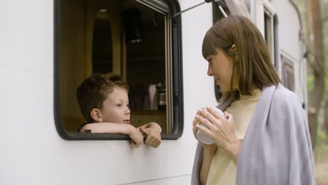 Mother-and-son-talking-by-the-campervan-in-the-forest