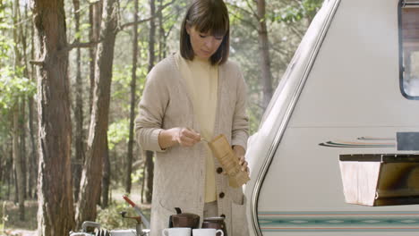 Smiling-woman-making-coffee-at-the-camping-in-the-forest