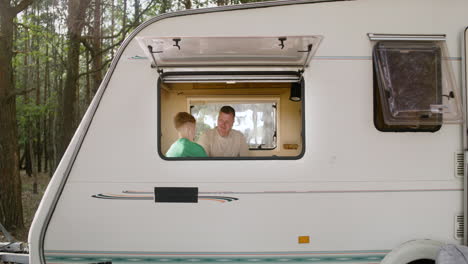 Father-and-son-playing-chess-sitting-on-the-campervan-bed