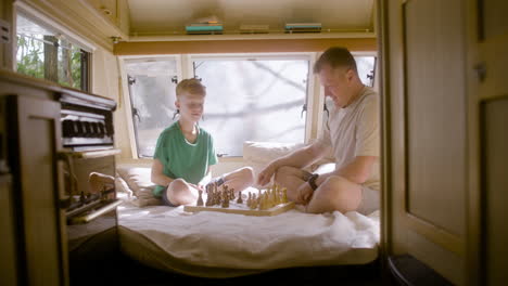 Vater-Und-Sohn-Spielen-Schach-Auf-Dem-Bett-Des-Wohnmobils