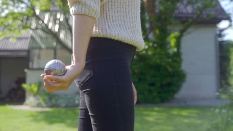 Close-up-view-of-a-woman-hand-holding-a-petanque-ball-and-getting-ready-to-throw-it-in-the-park