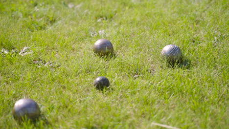 Side-view-of-pentanque-balls-on-the-grass-in-the-park