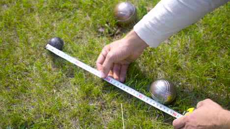 Top-view-of-a-caucasian-young-man-calculating-distance-between-petanque-balls-in-the-park