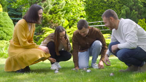 Side-view-of-a-group-of-men-and-women-friends-calculating-distance-between-petanque-balls-in-the-park