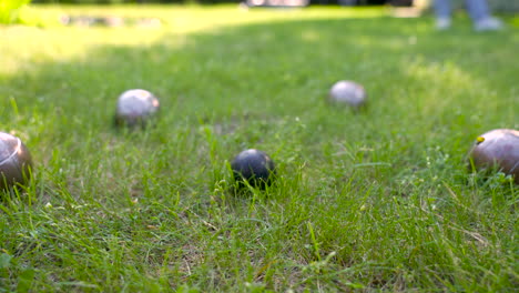 Close-up-view-of-some-metal-petanque-balls-on-the-grass-in-the-park