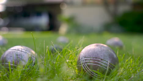 Close-up-view-of-a-metal-petanque-ball-on-the-grass,-then-the-player-throw-another-ball-nearby