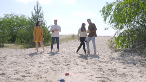 Front-view-of-group-of-women-and-men-friends-playing-petanque-on-the-beach-on-a-sunny-day