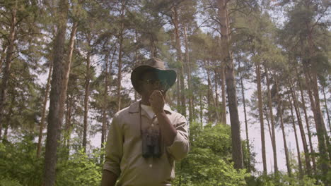 Lower-view-of-african-american-forest-warden-talking-on-walkie-talkie-in-the-woods