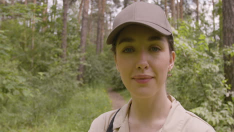 Close-up-view-of-caucasian-female-forest-warden-wearing-cap-and-looking-at-camera-with-crossed-arms-in-the-woods