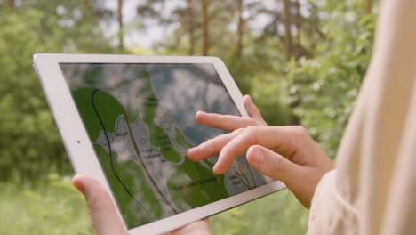 Close-up-view-of-the-hands-of-caucasian-female-forest-warden-watching-a-forest-map-on-a-tablet