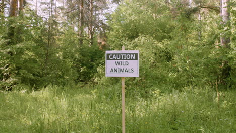 Kamera-Zoomt-Auf-Ein-Schild,-Um-Zu-Warnen,-Dass-Es-Wilde-Tiere-Im-Wald-Gibt