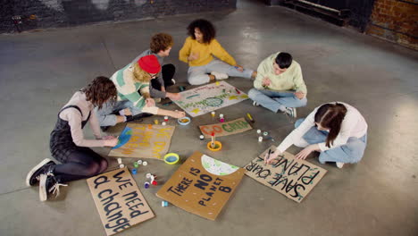 Draufsicht-Auf-Junge-Umweltaktivisten,-Die-Auf-Dem-Boden-Sitzende-Plakate-Malen