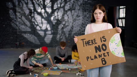 Serious-young-environmental-activist-holding-a-cardboard-with-There-is-no-planet-B"-inscription-and-looking-at-the-camera"