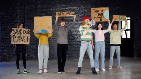 Young-environmental-activists-with-placards-and-megaphone-protesting-against-climate-change-inaction