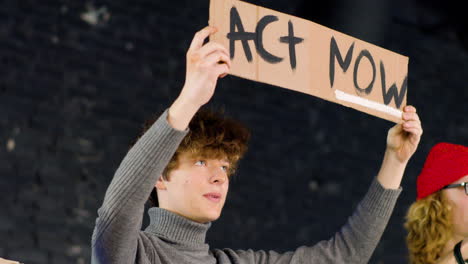 Young-environmental-activist-holding-a-cardboard-with-Act-now"-inscription-and-protesting-against-climate-change-inaction"
