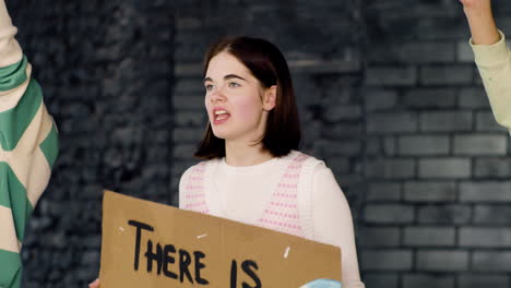 Young-environmental-activist-holding-a-cardboard-with-There-is-no-planet-B"-inscription-and-protesting-with-her-friends-against-climate-change-inaction"
