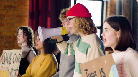 Side-view-of-young-environmental-activists-with-placards-and-megaphone-protesting-against-climate-change-inaction