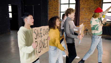 Side-view-of--young-environmental-activists-with-placards-and-megaphone-walking-and-protesting-against-climate-change-inaction