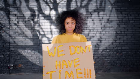 Ernsthafter-Junger-Umweltaktivist-Hält-Einen-Karton-Mit-Der-Aufschrift-„Wir-Haben-Keine-Zeit“-Und-Schaut-In-Die-Kamera“