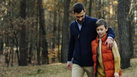 Caucasian-man-walking-and-talking-in-the-forest-with-his-little-son