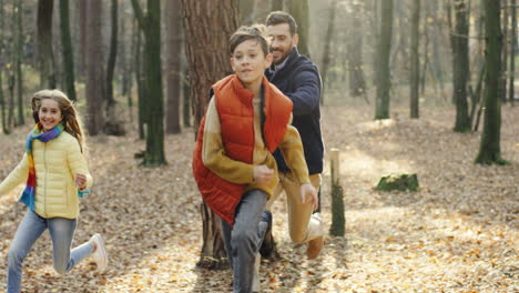 Caucasian-happy-father-with-his-daughter-and-little-son-running-and-playing-in-the-forest