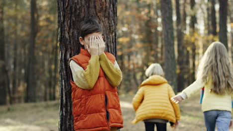 Cute-Caucasian-children-playing-hide-and-seek-in-the-middle-of-the-forest-on-a-sunny-day