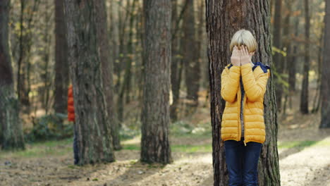 Cute-Caucasian-children-playing-hide-and-seek-in-the-middle-of-the-forest-on-a-sunny-day