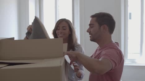 Young-couple-opening-box-with-pillows-and-smiling