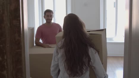 Happy-woman-coming-into-room,-carrying-box-with-different-stuff-and-kissing-her-husband