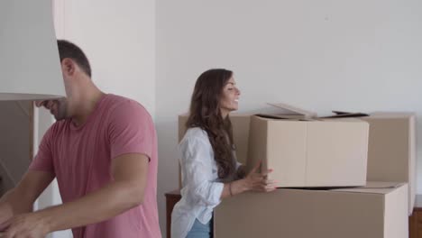 Happy-man-giving-cardboard-boxes-to-girlfriend-who-putting-them-on-each-other