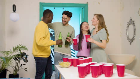 Glückliche-Multiethnische-Junge-Freunde,-Die-Sich-Umarmen,-Zu-Hause-Anstoßen-Und-Bier-Trinken