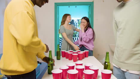 Multiethnic-young-friends-playing-beer-pong-at-home