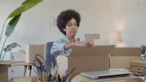 Young-female-entrepreneur-preparing-cardboard-parcel