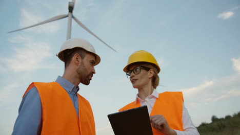 Close-up-view-of-two-Caucasian-male-and-female-engineers-discussing-some-problems-at-the-wind-station-of-renewable-energy
