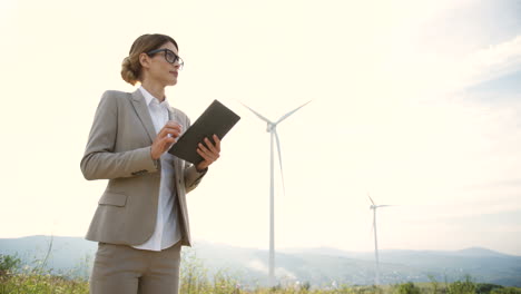 Lower-view-of-caucasian-woman-engineer-using-a-tablet-at-wind-station-of-renewable-energy