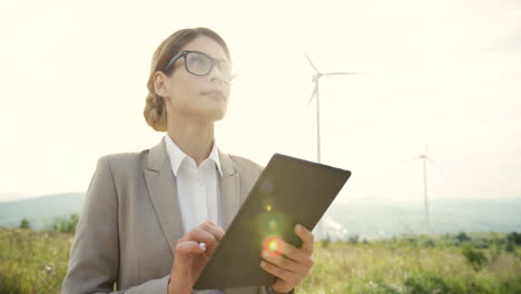 Close-up-view-of-caucasian-woman-engineer-using-a-tablet-at-wind-station-of-renewable-energy