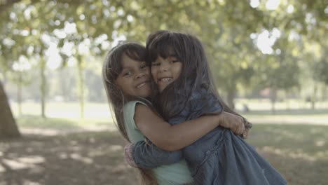 Cute-Latin-little-girls-hugging-each-other-and-smiling-in-the-park