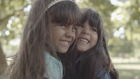Closeup-portrait-of-Latin-little-girls-hugging-each-other,-smiling-and-kissing-in-the-park