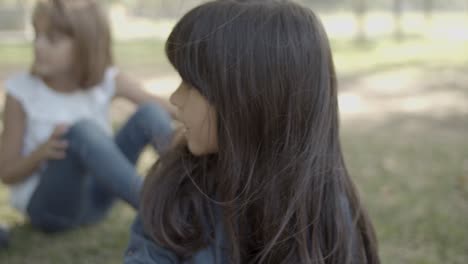 Portrait-of-cute-long-haired-girl-sitting-in-the-park-with-friends-and-looking-around