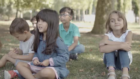 Multiethnische-Mädchen-Und-Jungen-Sitzen-Zusammen-Auf-Gras-Im-Park