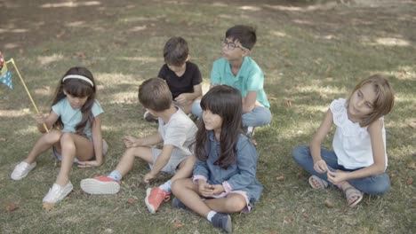 Multiethnische-Kinder-Sitzen-Zusammen-Auf-Gras-Im-Park-Und-Entspannen-Sich