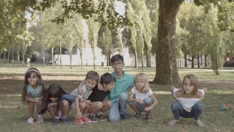 Joyful-multiethnic-children-squatting-and-standing-up-in-the-park
