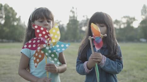 Zwei-Langhaarige-Lateinamerikanische-Mädchen-Blasen-Auf-Papierfächern-Im-Park