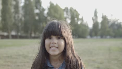 Porträt-Eines-Süßen-Lateinischen-Mädchens,-Das-Im-Park-Steht,-In-Die-Kamera-Lächelt-Und-Springt