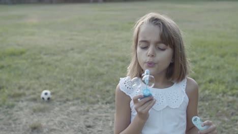 Caucasian-girl-blowing-bubbles-with-closed-eyes-in-the-park