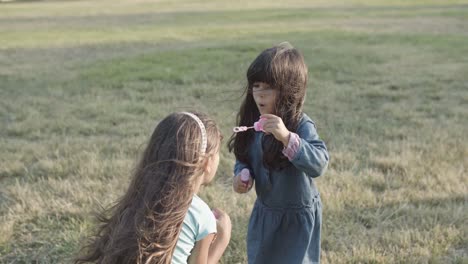 Cute-Latin-little-girls-blowing-bubbles-on-each-other-in-the-park