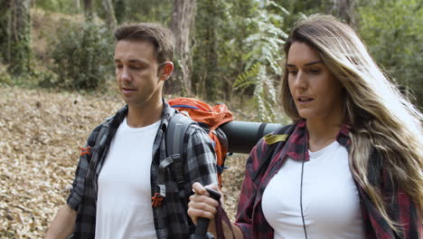 Couple-of-tourists-talking-while-carrying-camping-backpacks