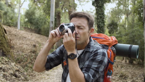 Backpacker-guy-with-photo-camera-taking-pictures-of-forest