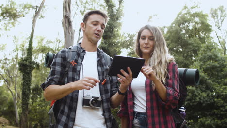 Couple-of-young-backpackers-checking-route-on-tablet
